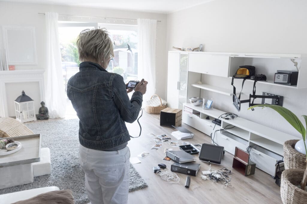 Woman photographing results of a home burglary.